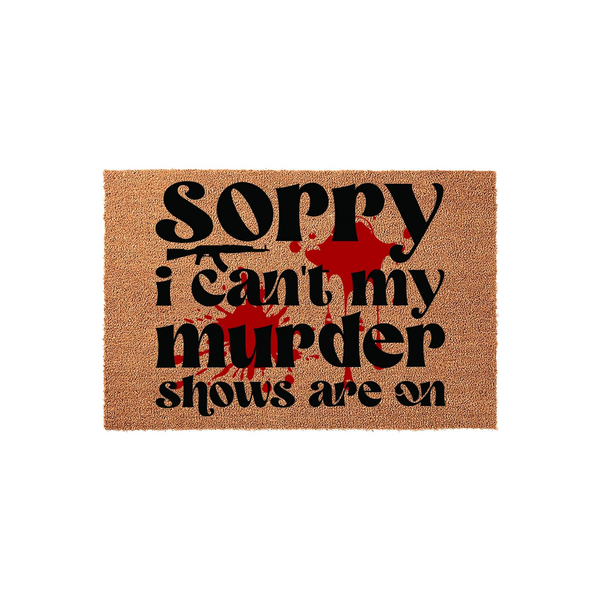 Funny True Crime Doormat featuring a natural coir texture with bold black text that reads Sorry I Can't My Murder Shows Are On, accented by a graphic red blood splatter design and a silhouette of a weapon for a dark humor home
