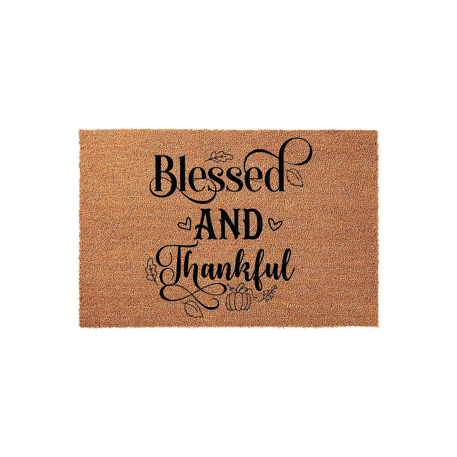Blessed and Thankful coir doormat featuring black script lettering, decorative hearts, and small pumpkin illustrations on a natural brown fiber background, perfect for a cozy fall porch or autumn home entrance decor.