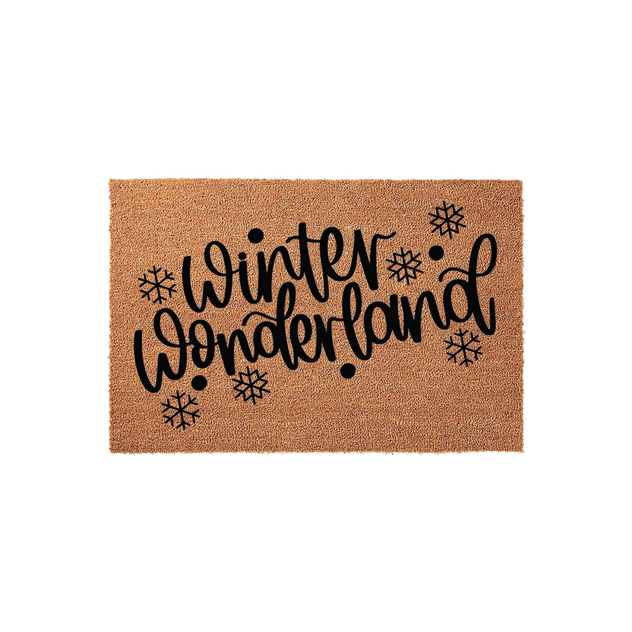 Winter Wonderland coir doormat featuring natural brown coconut fiber texture and bold black script lettering, accented with decorative snowflake illustrations for a festive holiday entryway decor piece on a plain white background.