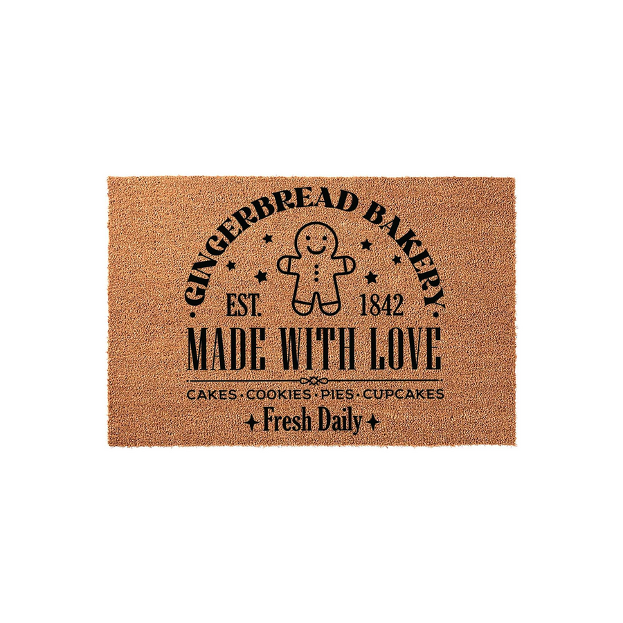 Gingerbread Bakery coir doormat featuring a cute gingerbread man graphic, black text reading Made With Love, and a list of baked goods like cakes and cookies, all set against a natural brown textured fiber background for a
