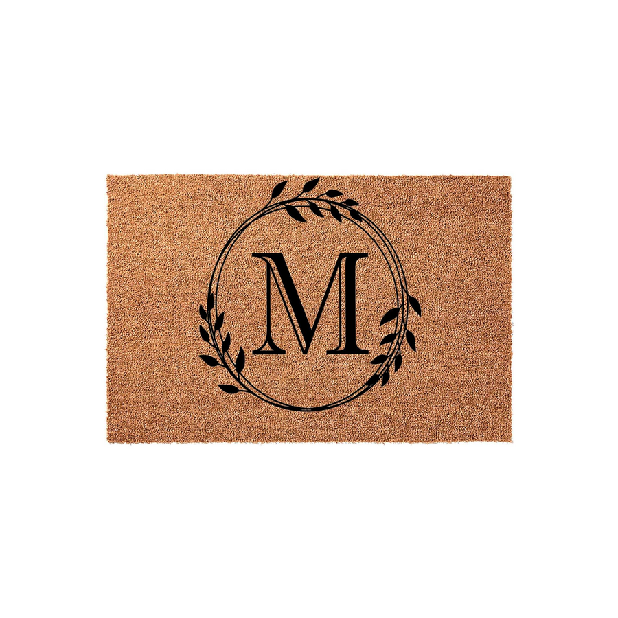 Personalized Monogram Coir Doormat featuring a large black letter M centered inside a delicate hand-drawn botanical leaf wreath, set against a natural tan textured coconut fiber background for a classic farmhouse entryway decor
