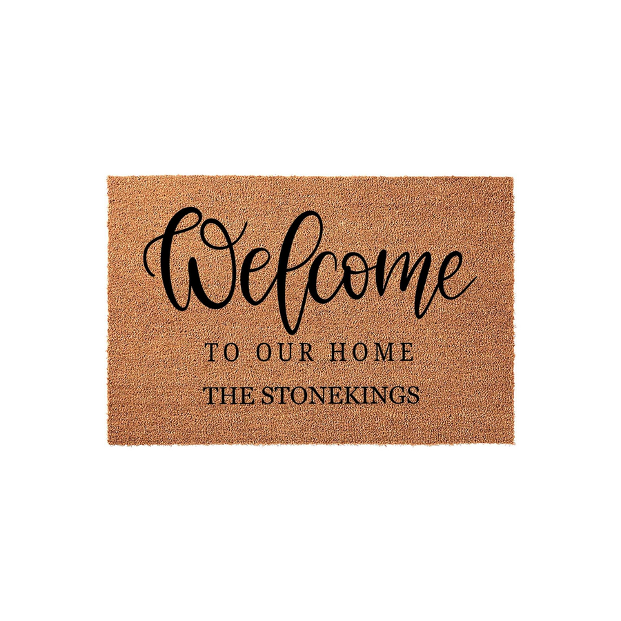 Personalized Welcome To Our Home Doormat featuring a natural coir fiber texture with elegant black script and serif lettering, providing a custom entryway floor mat that displays a family name for a warm and inviting front porch