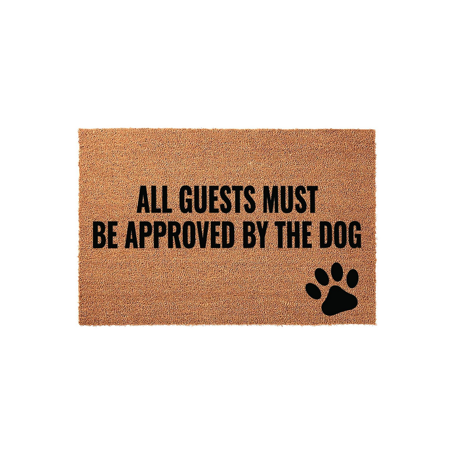Funny Dog Lover Doormat featuring a natural coir texture with the bold black text All Guests Must Be Approved By The Dog and a matching paw print graphic, perfect for a pet-friendly home entrance on a clean white studio
