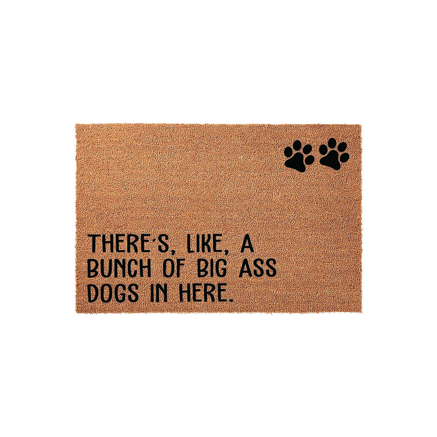 Funny Dog Lover Coir Doormat featuring the text There is like a bunch of big ass dogs in here printed in bold black letters, accented with two black paw prints on a natural brown coconut fiber mat against a clean white background.