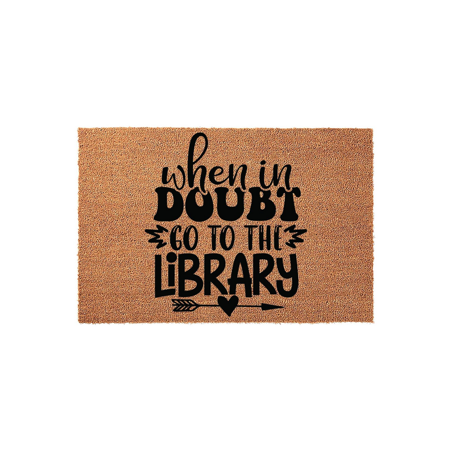 When in Doubt Go to the Library coir doormat featuring bold black typography and a decorative arrow with a heart icon, providing a charming and literary welcome for any book lover's front porch or home entryway decor.