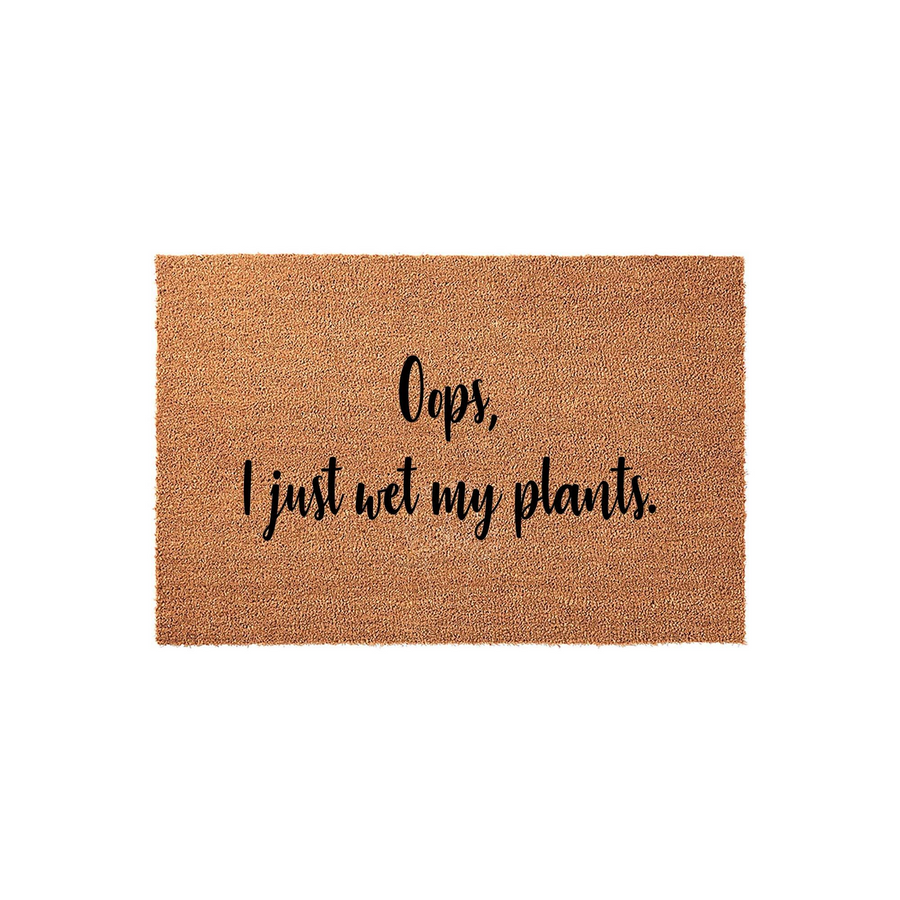 Oops I Just Wet My Plants Coir Doormat featuring a natural brown fiber texture and bold black script lettering, making it a humorous and functional outdoor welcome mat for any plant lover's front porch or entryway decor.