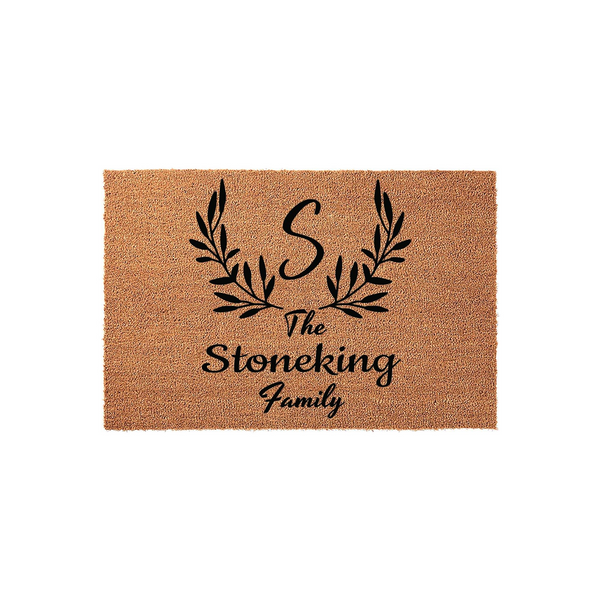 Personalized family name coir doormat featuring a large script initial letter S centered above a decorative black leaf wreath design, creating a welcoming entrance piece for any home with a natural tan fiber texture and black ink.