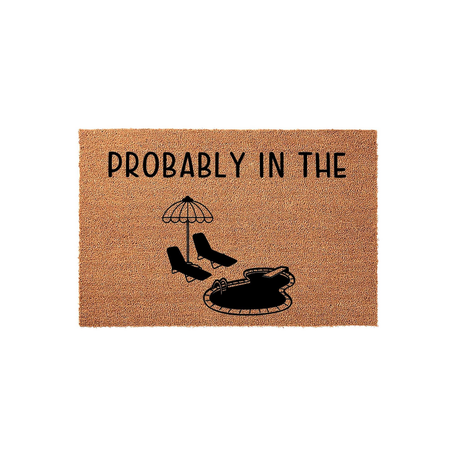 Probably In The Pool Coir Doormat featuring a black graphic of two lounge chairs under an umbrella next to a swimming pool, set against a natural tan textured background for a fun summer outdoor entryway decor piece.