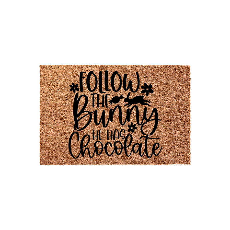 Follow the Bunny He Has Chocolate Easter doormat featuring a natural coir fiber texture with black printed text, a leaping rabbit silhouette, and small flower accents for a festive spring porch decor addition to your home
