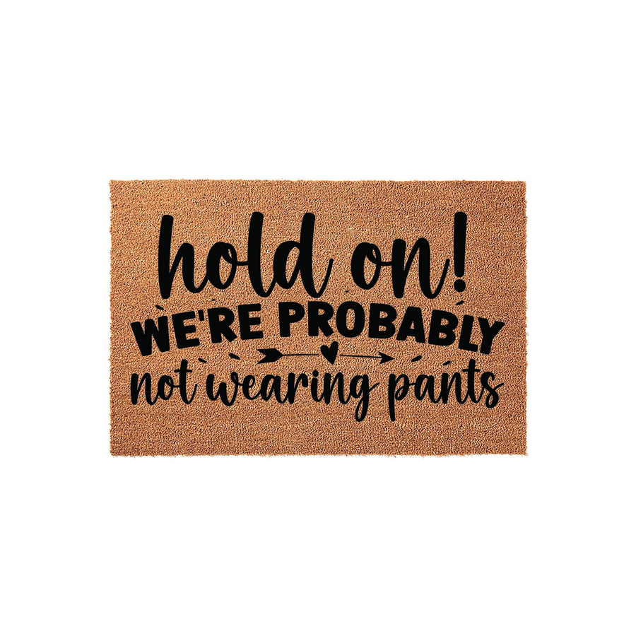 Funny coir doormat featuring the text hold on we are probably not wearing pants in a mix of bold and script black lettering, set against a natural brown coconut fiber background for a humorous and welcoming front porch entryway