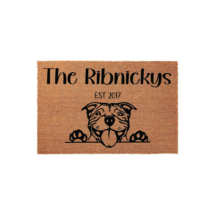 Personalized Pit Bull doormat featuring a cute illustrated dog peeking over the bottom edge, with custom family name text and established year printed in black on a natural tan coir fiber background for a welcoming front porch