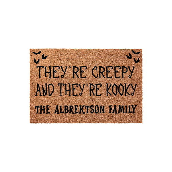 Personalized Halloween doormat featuring a natural coir texture with black text that reads They Are Creepy And They Are Kooky, customized with a family name, and decorated with small black bats in the top corners for a spooky