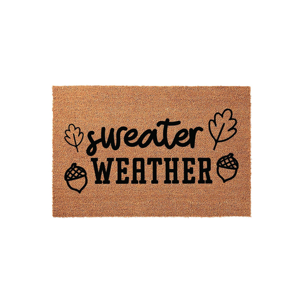Sweater Weather Fall Doormat featuring a natural coir texture with black printed text and decorative autumn leaf and acorn illustrations, creating a cozy seasonal welcome for your front porch entryway during the crisp autumn