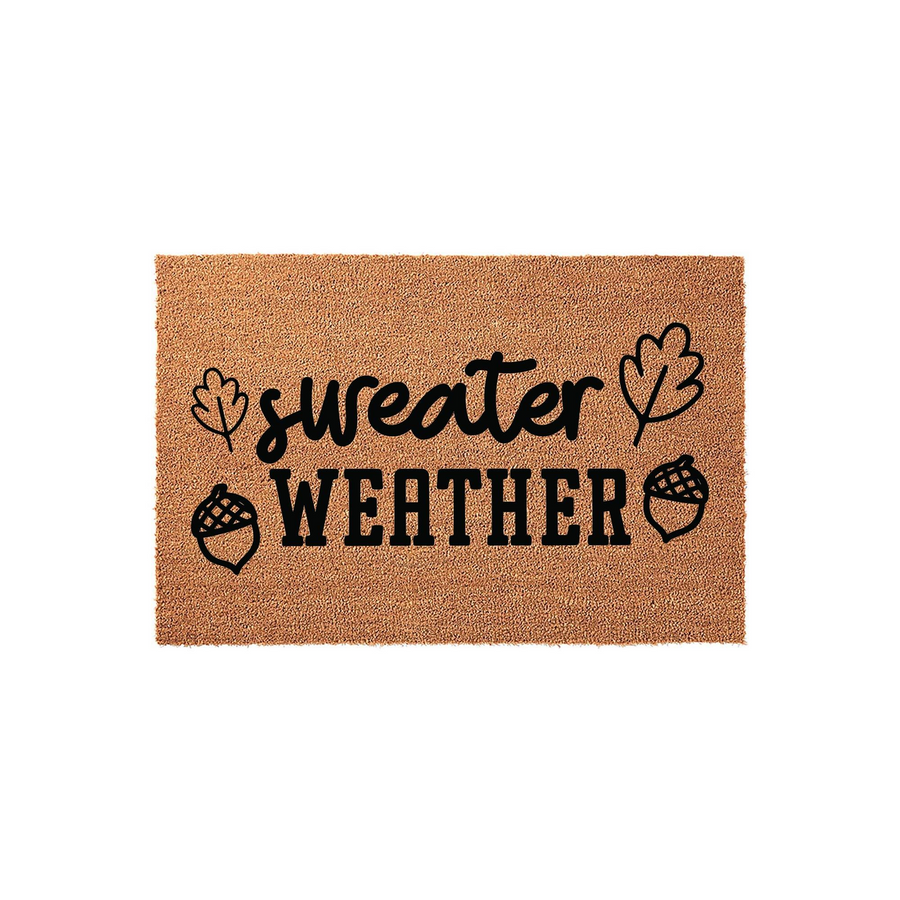 Sweater Weather Fall Doormat featuring a natural coir texture with black printed text and decorative autumn leaf and acorn illustrations, creating a cozy seasonal welcome for your front porch entryway during the crisp autumn