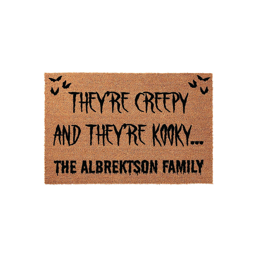 Personalized Halloween doormat featuring a natural coir texture with black text that reads They are creepy and they are kooky, accented by small flying bat silhouettes and a customizable family name on a plain white studio