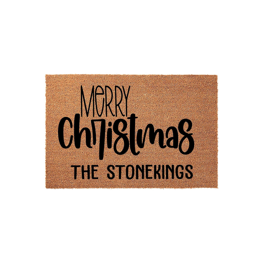 Personalized Merry Christmas coir doormat featuring a natural brown fiber texture with bold black lettering that displays the holiday greeting and a customizable family name, set against a clean white background for a festive
