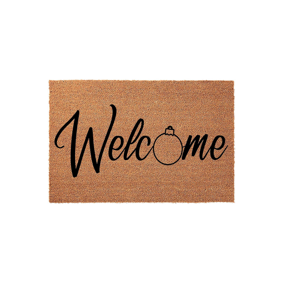 Christmas Welcome Doormat featuring a natural coir texture and black script lettering, where the letter o is replaced by a simple line-art holiday ornament design, creating a festive entryway accent for the winter holiday season.
