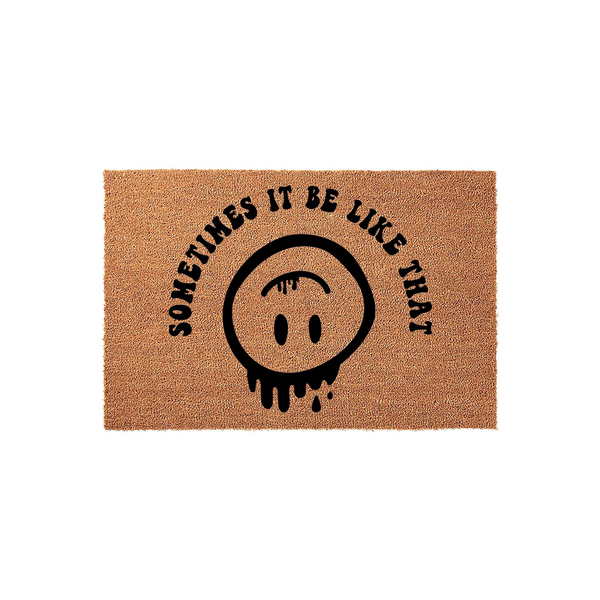 Sometimes It Be Like That Coir Doormat featuring a black printed design of a melting, upside-down smiley face, set against a natural brown textured fiber background for a fun and quirky entryway decor piece for your home.