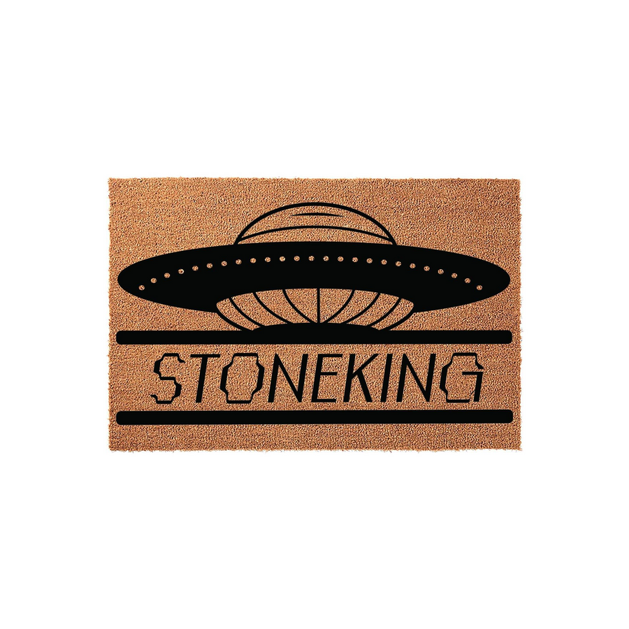 Personalized UFO space themed doormat featuring a black flying saucer graphic above a custom family name text area, printed on a natural tan coir fiber mat that adds a fun sci-fi touch to any front porch or entryway home decor.