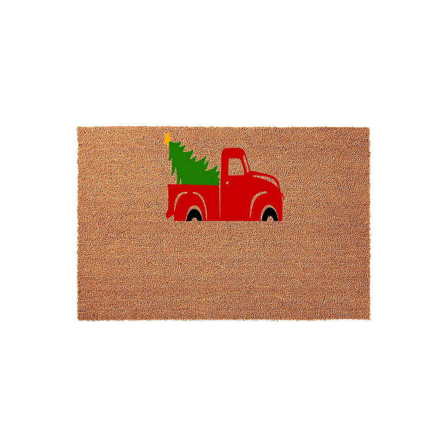 Christmas Red Truck Coir Doormat featuring a festive illustration of a bright red vintage pickup truck carrying a green pine tree with a yellow star on top, set against a natural tan textured coir background for a holiday