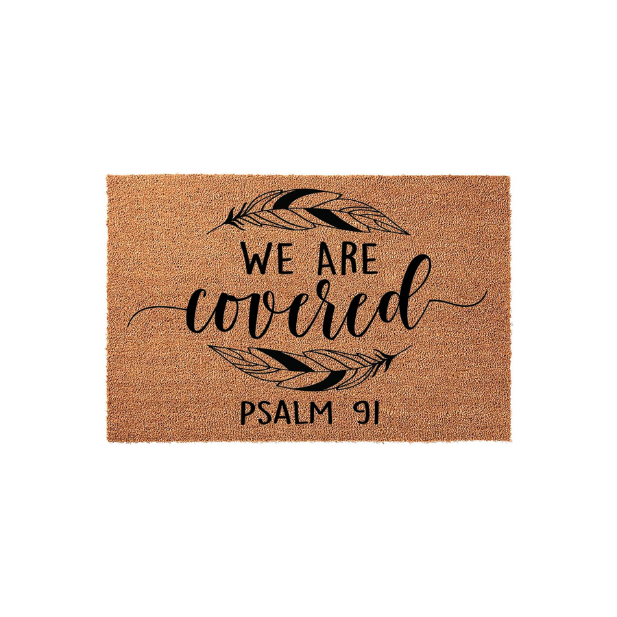 Psalm 91 We Are Covered coir doormat featuring a natural tan fiber texture with black printed text and two stylized feathers, creating a welcoming and faith-inspired entryway decor piece for a home on a clean white background.