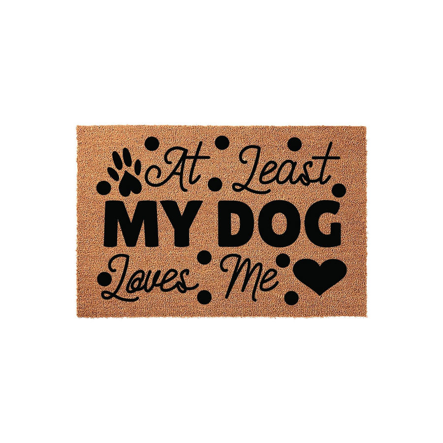 At Least My Dog Loves Me coir doormat featuring a natural tan fiber texture, bold black typography, a decorative paw print, and a heart icon, creating a humorous and welcoming entryway accessory for any pet owner's home front