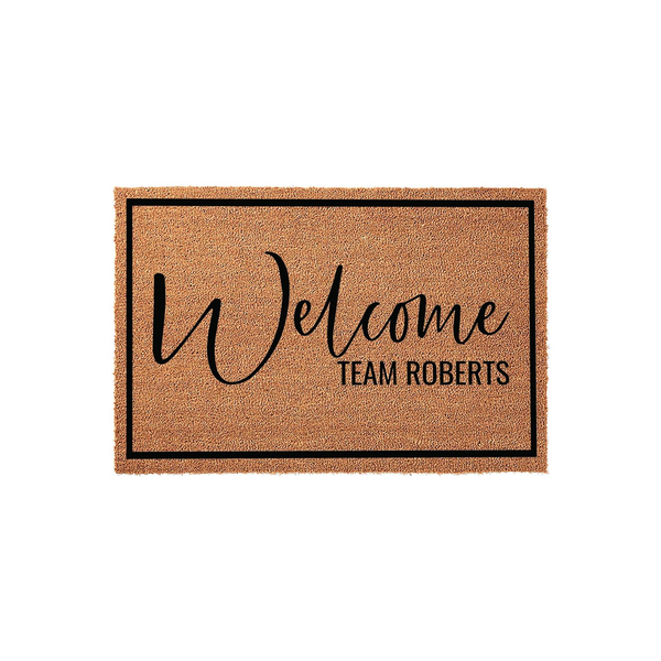 Personalized family name coir doormat featuring a natural brown fiber texture with a black border, displaying the word Welcome in elegant script and a custom family name in clean, bold lettering on a plain white studio background.
