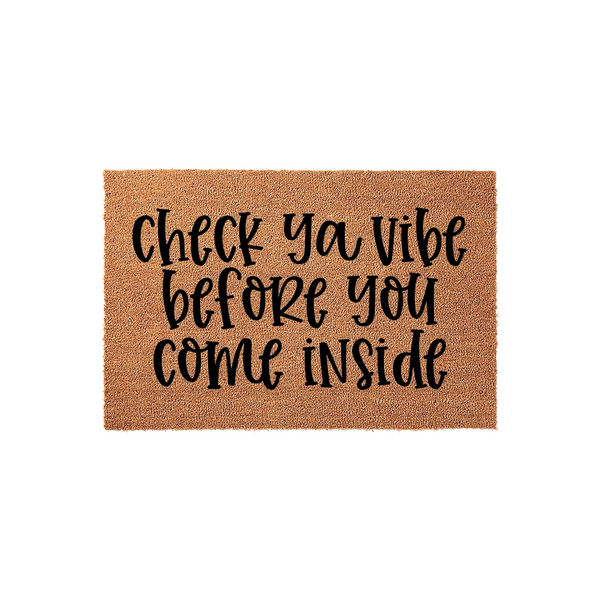 Check Ya Vibe Before You Come Inside doormat featuring a natural brown coir texture with bold black script lettering, providing a fun and welcoming entrance decor piece for your front porch or home entryway on a clean white