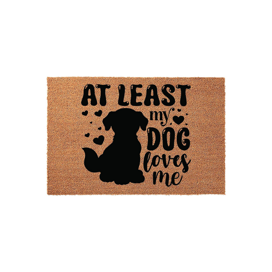 At Least My Dog Loves Me coir doormat featuring a black silhouette of a sitting dog surrounded by small hearts, printed on a natural tan fiber mat that adds a fun and welcoming touch to any front porch or entryway decor.