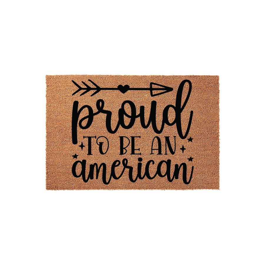 Proud to be an American coir doormat featuring a rustic brown natural fiber texture with black printed text, a decorative arrow, and small stars, making it a patriotic front porch decor piece for any home entrance.