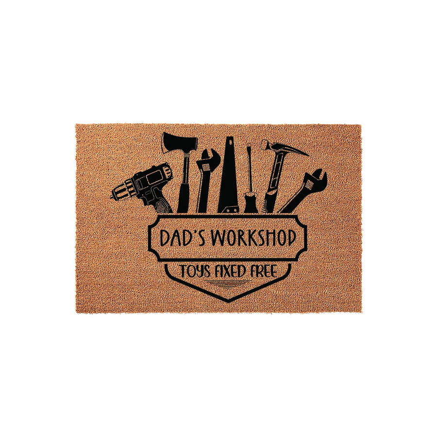 Dad's Workshop coir doormat featuring a black graphic of various hand tools and a drill above a shield emblem that reads Dad's Workshop and Toys Fixed Free, set against a plain white background for a clean, rustic home entryway