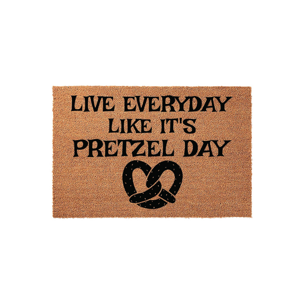 Live Everyday Like It's Pretzel Day coir doormat featuring a humorous quote and a black pretzel graphic printed on a natural tan fiber background, creating a fun and welcoming entrance for any fan of the iconic television show.