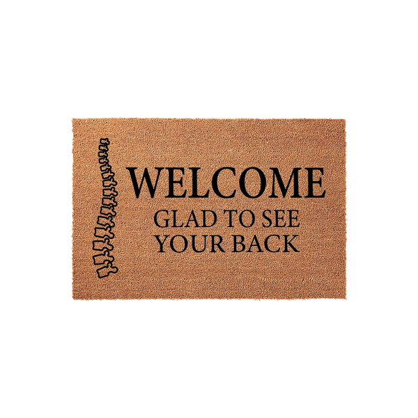 Funny Chiropractic Welcome Doormat featuring a human spine illustration on the left side and the text Welcome Glad To See Your Back printed in black on a natural brown coir fiber mat, perfect for a chiropractor office or home