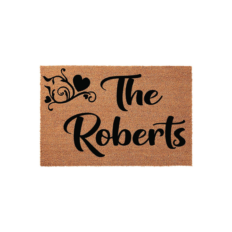 Personalized family name coir doormat featuring a rustic brown texture with black script text that reads The Roberts, accented by a decorative flourish and heart design on a clean white background for a welcoming home entrance.