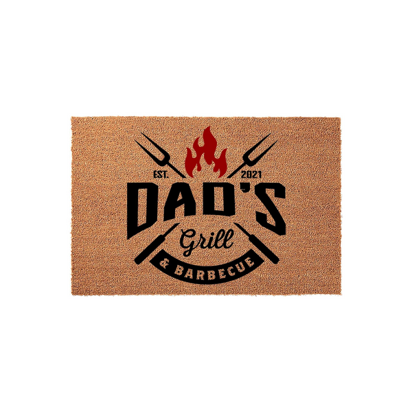 Dad's Grill and Barbecue coir doormat featuring a bold black and red design with crossed grilling forks, a flame icon, and the text Dad's Grill and Barbecue established in 2021, set against a plain white studio background.