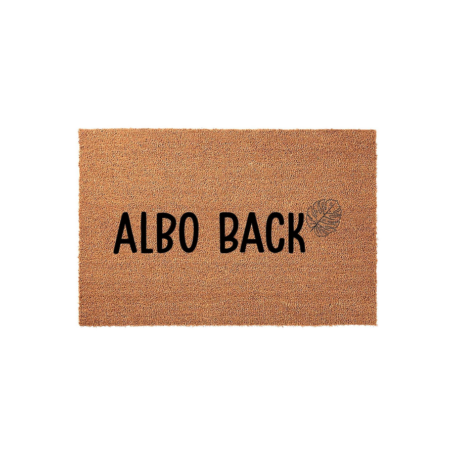 Albo Back coir doormat featuring a natural brown fiber texture and bold black lettering, accented by a delicate line-art monstera leaf illustration on a clean white background for a modern housewarming entryway decor style.