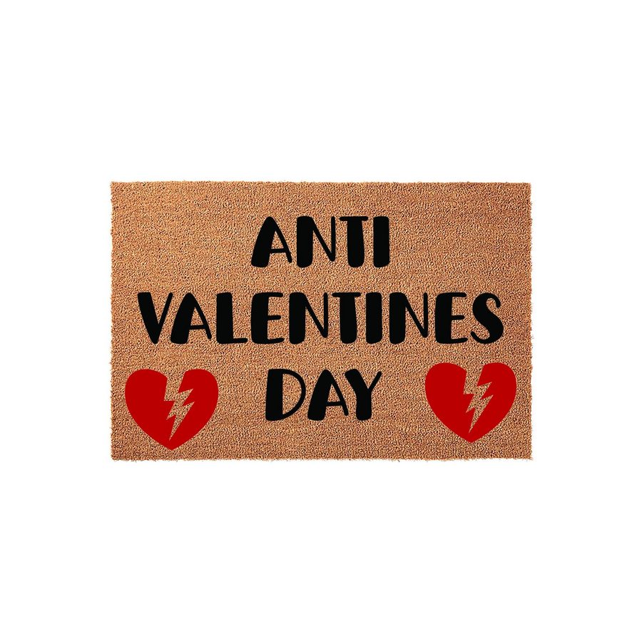 Anti Valentines Day coir doormat featuring bold black text and two red broken heart icons with lightning bolt cracks, displayed on a plain white background for a humorous and sarcastic seasonal home decor entrance statement.