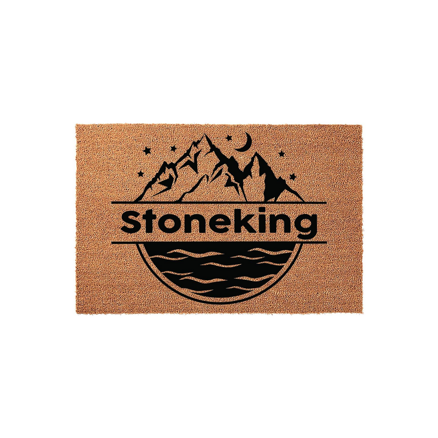 Personalized Mountain and Lake Coir Doormat featuring a black graphic of jagged peaks, a crescent moon, and rippling water, with a central horizontal line designed for a custom family name on a natural tan textured fiber