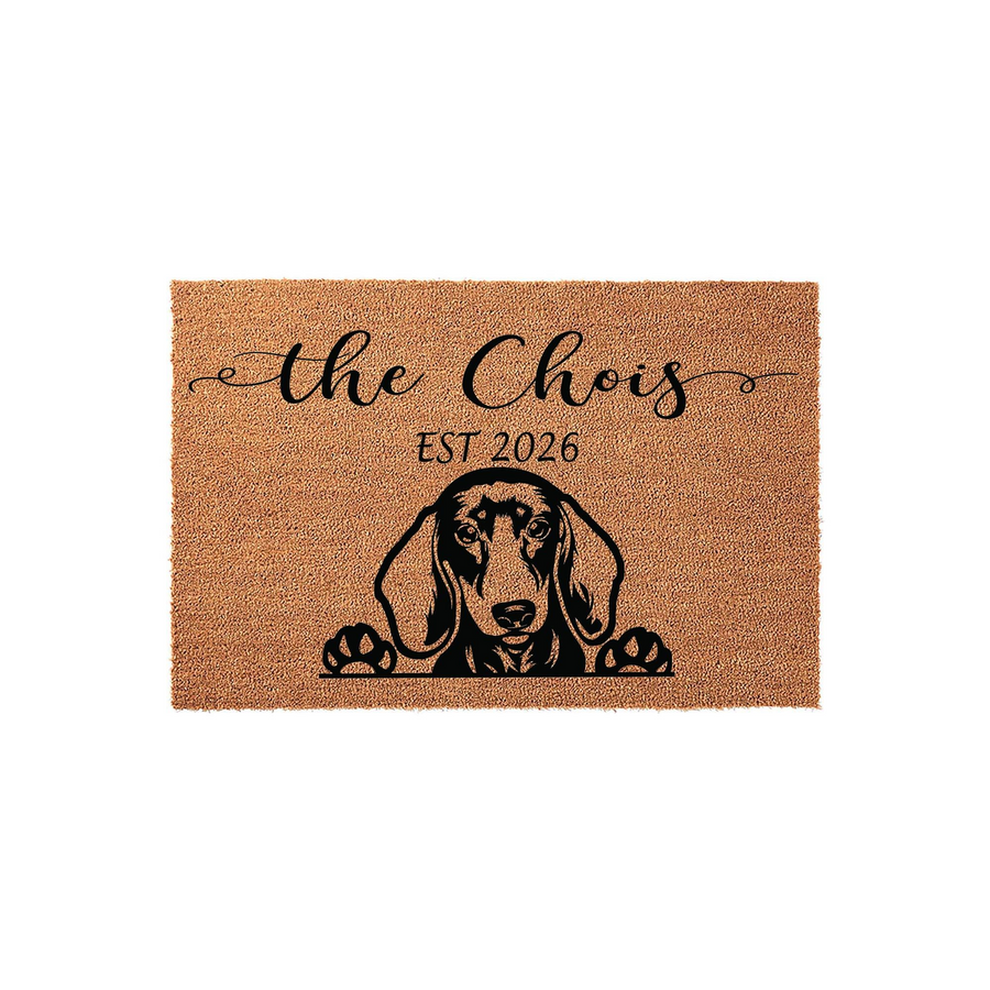 Personalized Dachshund doormat featuring a cute dog illustration peeking over the bottom edge, printed on natural coir fiber with a custom family name and established year in elegant black script and classic serif typography.