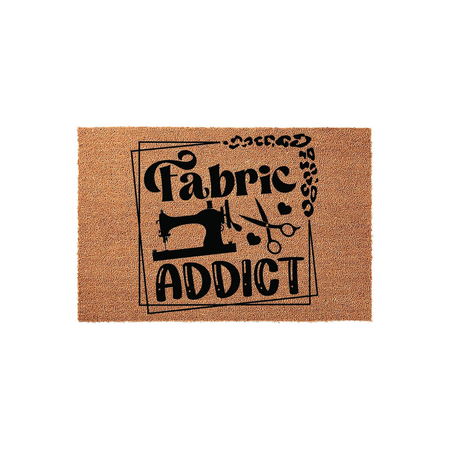 Fabric Addict coir doormat featuring a black printed design of a sewing machine, scissors, and leopard print accents, set against a natural brown fiber background that is ideal for a sewing room or craft space entrance.