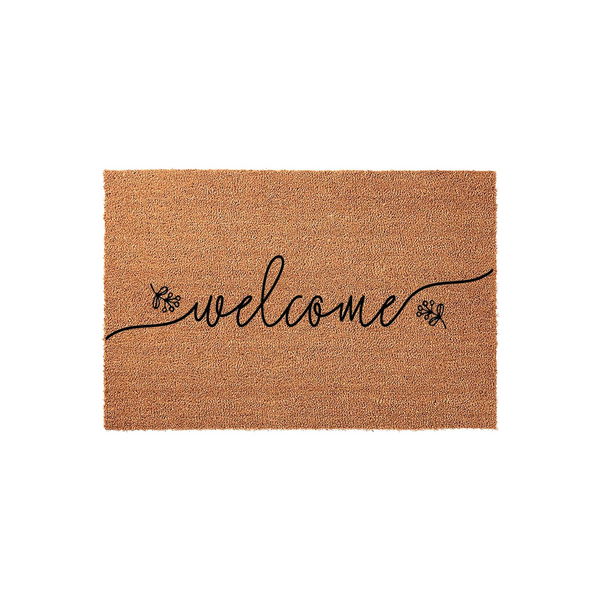 Natural coir welcome doormat featuring elegant black cursive script lettering centered on the mat, accented by delicate floral sprigs on either side of the word welcome, set against a clean white background for a modern farmhouse