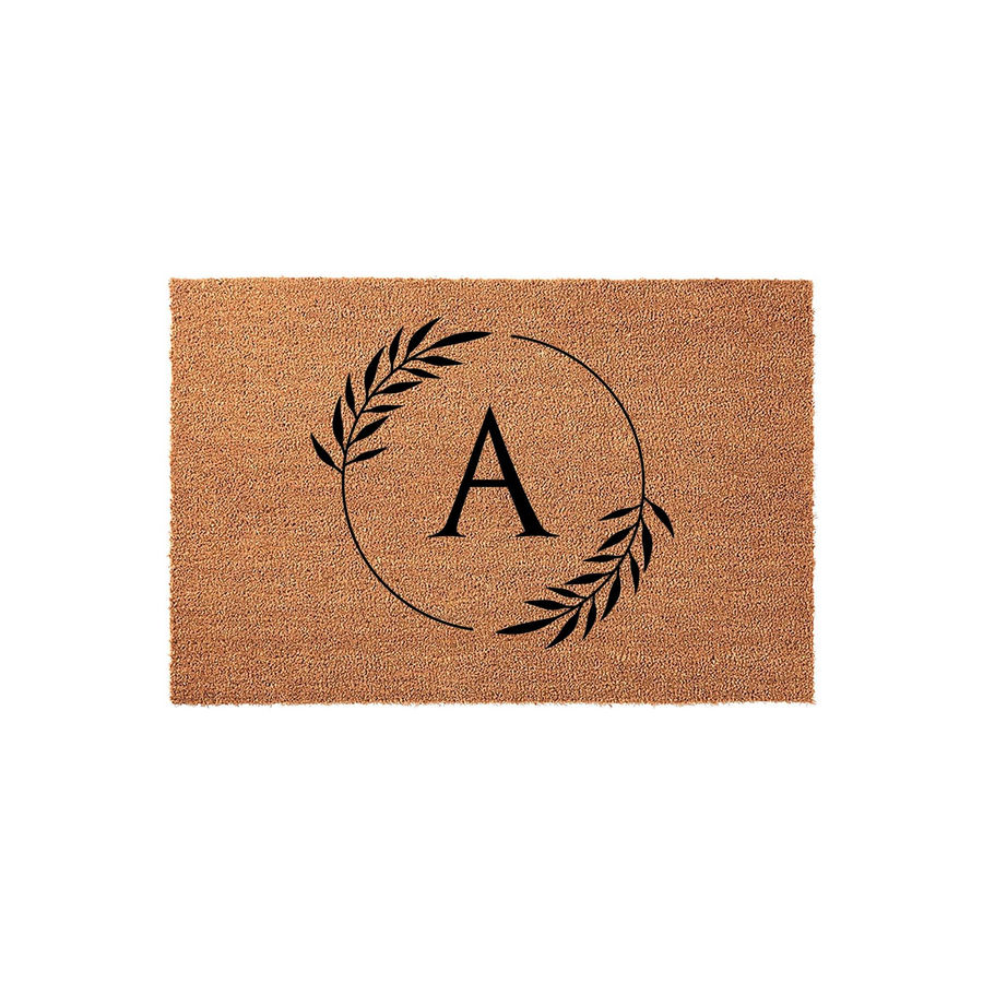 Personalized monogram coir doormat featuring a black letter A centered inside a delicate botanical leaf wreath, providing a natural and rustic aesthetic for a front porch entrance that welcomes guests to a family home.