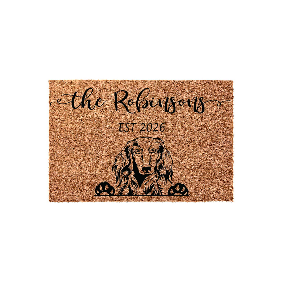 Personalized Long-Haired Dachshund Coir Doormat featuring a custom family name and established year, showcasing a detailed black illustration of a long-haired dachshund peeking over the bottom edge on a natural brown fiber