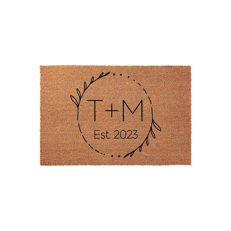 Personalized coir doormat featuring a minimalist black line art wreath design, centered with custom initials and an established year on a natural brown fiber background, perfect for a modern farmhouse entryway or wedding home