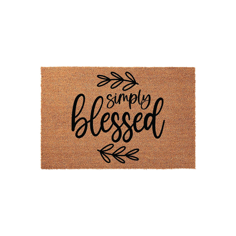 Simply Blessed coir doormat featuring a natural tan fiber texture and black script lettering, accented by simple hand-drawn leaf sprigs above and below the text to create a welcoming farmhouse style entrance for your front porch.