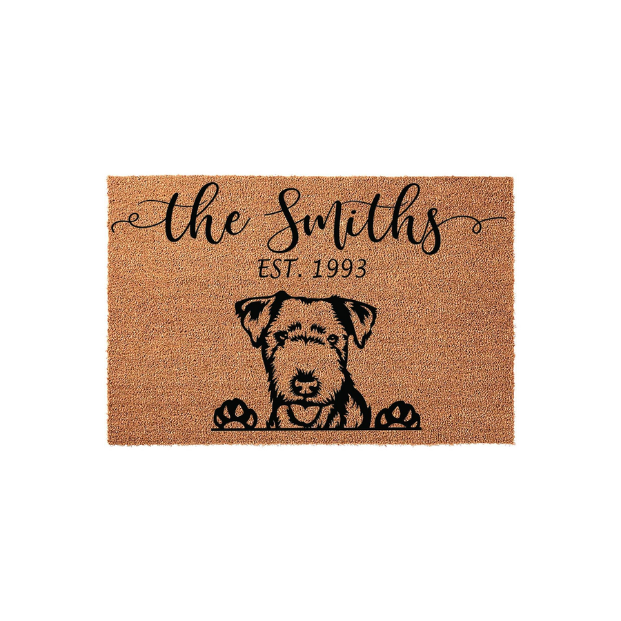 Personalized Airedale Terrier doormat featuring a cute dog illustration peeking over the bottom edge, with custom family name and established year text printed in black on a natural coir fiber background for a welcoming home