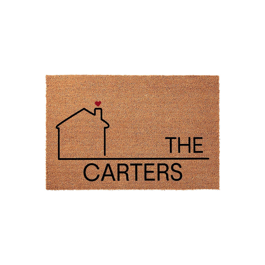 Personalized family name coir doormat featuring a minimalist black house outline with a small red heart on the chimney, displaying the text The Carters on a natural brown textured fiber background for a welcoming home entrance.