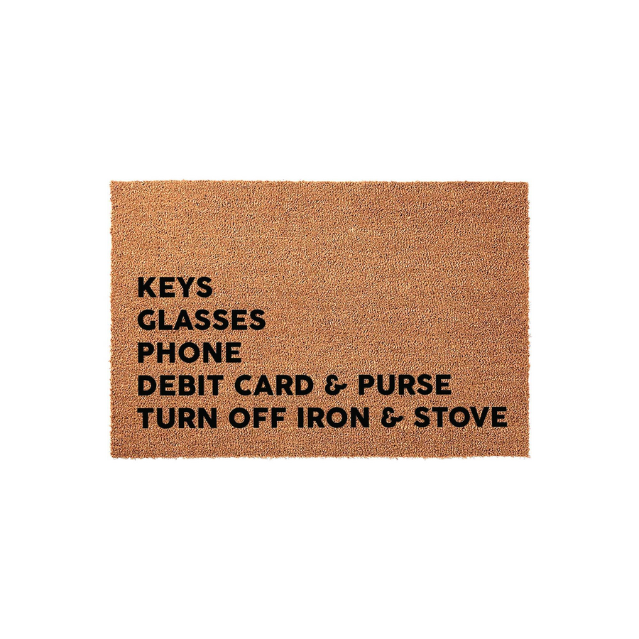 Funny Reminder Doormat featuring a natural coir texture with bold black text that lists essential items like keys, glasses, phone, and debit card, plus a helpful reminder to turn off the iron and stove before leaving your home.