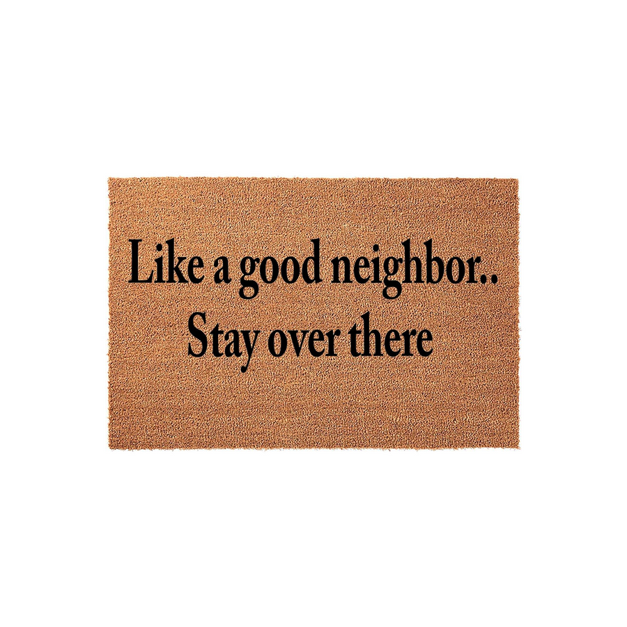Funny coir doormat with the text Like a good neighbor, stay over there printed in bold black lettering, featuring a natural tan fiber texture that adds a humorous and welcoming touch to any front porch or entryway decor.