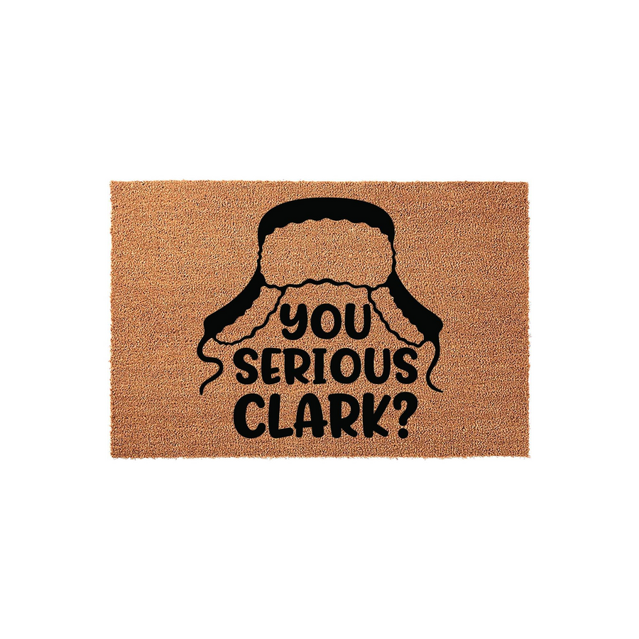 Funny Christmas movie quote doormat featuring a black graphic of a trapper hat and the text You Serious Clark? printed in bold letters on a natural tan coir fiber mat, perfect for a festive holiday entryway or front porch decor.